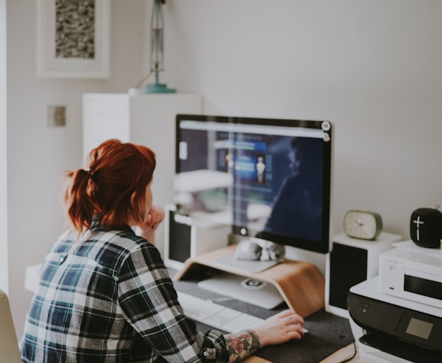 Persona che lavora da casa al PC con postazione organizzata e connessione internet veloce.