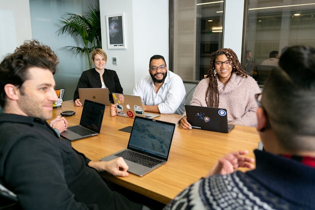 Lavoratori in ufficio che collaborano a un progetto digitale su laptop